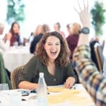Environment Bank employee laughing at summer conference, a woman in her forties with curly brown hair wearing a green shirt