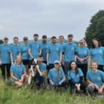 Fifteen Environment Bank employees on a charity walk, all between the ages of twenty and fifty, all wearing matching light-blue t-shirts