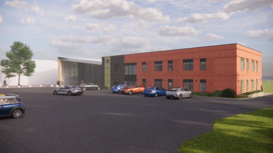 Visual render of the new school block, a 2-storey red brick building with a small car park in front.