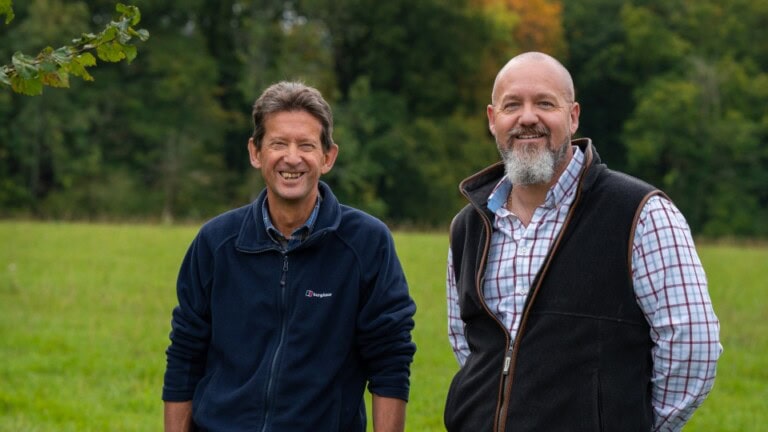 Environment Bank's landowner partner, Jon, at Chiddingfold Habitat Bank wearing a check shirt and body warmer - stood with his father, Neville, wearing a blue fleece