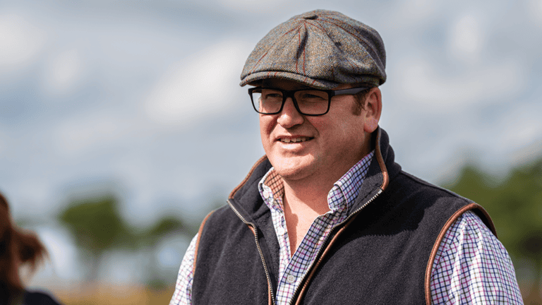 Principal land manager (north) Will, a middle-aged white man with black-framed glasses wearing a flat cap, dark grey gilet and white shirt with blue crossed stripes.
