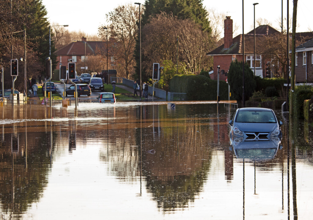 A flooded street in the UK, with cars half submerged in water.